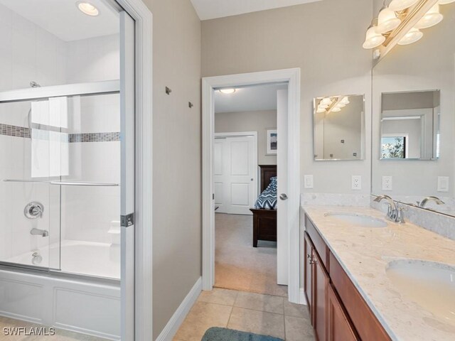 full bath featuring bath / shower combo with glass door, double vanity, a sink, ensuite bath, and tile patterned floors