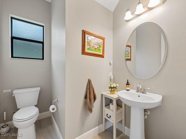 half bathroom featuring baseboards, a sink, and toilet