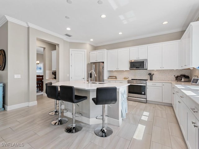 kitchen featuring a kitchen island with sink, decorative backsplash, stainless steel appliances, and a sink