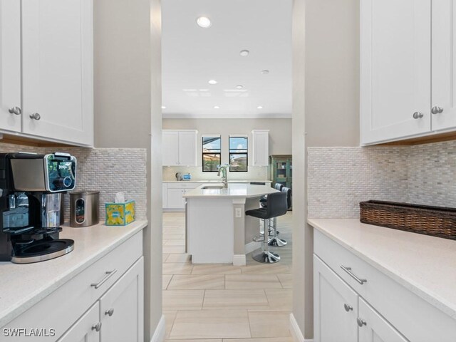 kitchen featuring tasteful backsplash, light countertops, white cabinets, and a sink