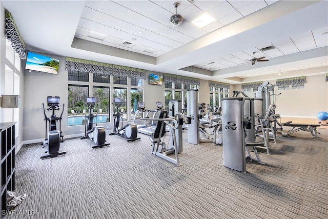 workout area featuring carpet, a tray ceiling, and baseboards