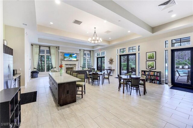 dining room with a fireplace, visible vents, a raised ceiling, and a notable chandelier