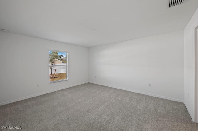 spare room with carpet floors, visible vents, and baseboards