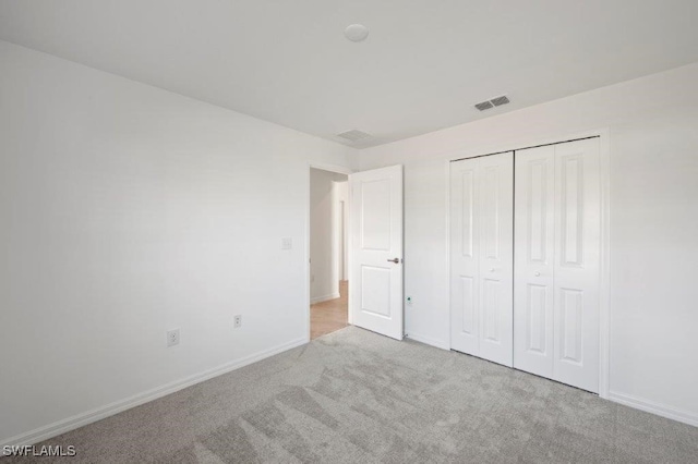 unfurnished bedroom with light carpet, a closet, visible vents, and baseboards