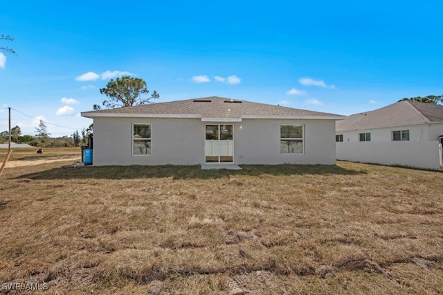 rear view of property with a lawn and stucco siding