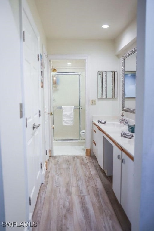 bathroom with toilet, wood finished floors, vanity, and a shower stall