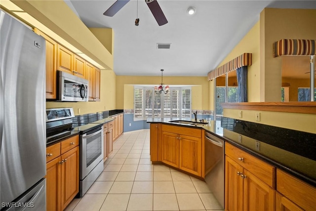 kitchen featuring light tile patterned floors, stainless steel appliances, a sink, visible vents, and brown cabinetry