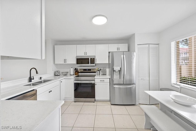 kitchen with light countertops, appliances with stainless steel finishes, a sink, and white cabinets