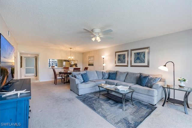 living area featuring light carpet, baseboards, a textured ceiling, and ceiling fan with notable chandelier