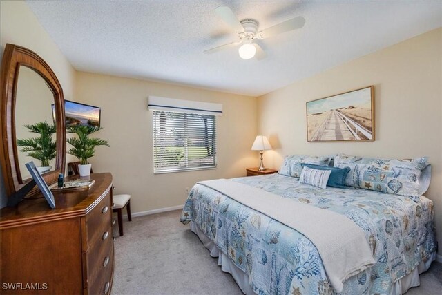 bedroom featuring light carpet, a textured ceiling, a ceiling fan, and baseboards