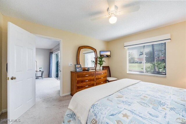 bedroom featuring light carpet, a ceiling fan, baseboards, and a textured ceiling