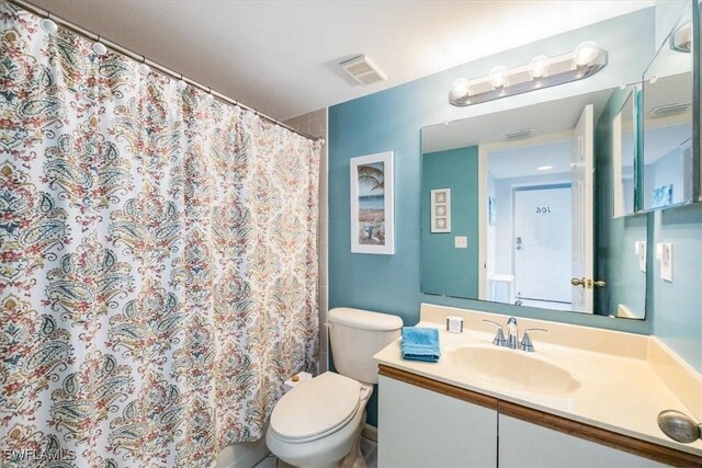 bathroom featuring a shower with shower curtain, visible vents, vanity, and toilet