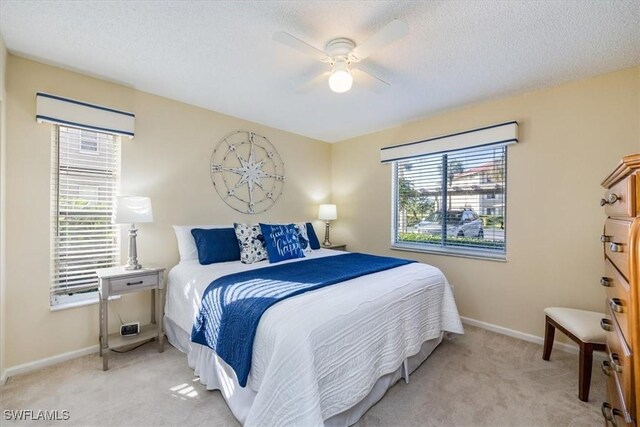 bedroom featuring light carpet, baseboards, and a textured ceiling