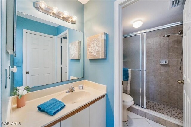 bathroom with visible vents, toilet, vanity, a shower stall, and tile patterned floors