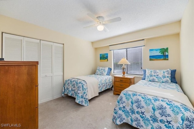 bedroom featuring a ceiling fan, a closet, light carpet, and a textured ceiling