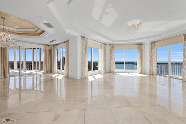 spare room with a notable chandelier, a raised ceiling, visible vents, a water view, and plenty of natural light