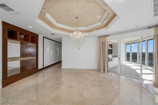 empty room with ornamental molding, a raised ceiling, visible vents, and baseboards