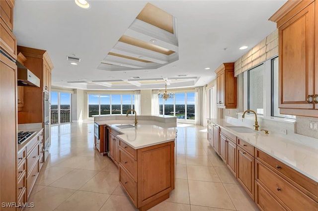 kitchen with gas stovetop, a center island with sink, a sink, and visible vents