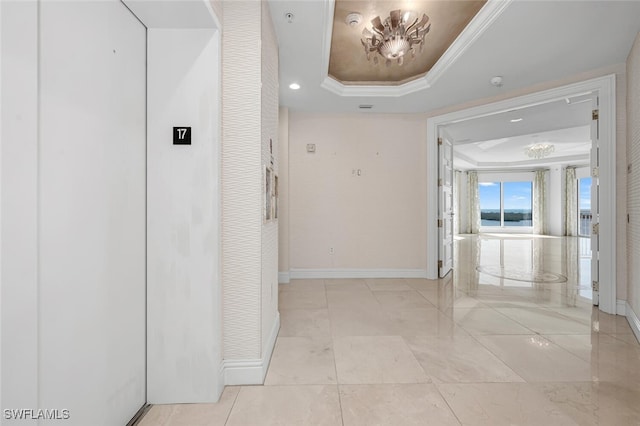 hallway with ornamental molding, a tray ceiling, baseboards, and elevator