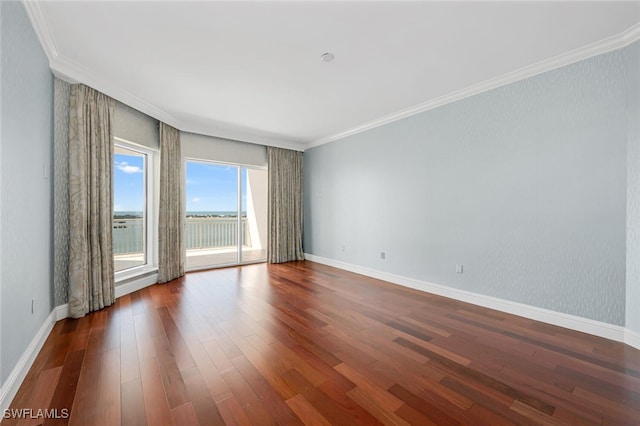 empty room featuring dark wood-style floors, ornamental molding, and baseboards