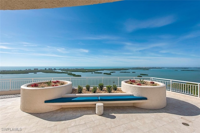 view of patio with a water view and fence