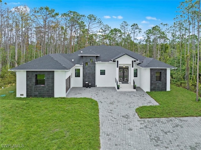 view of front of home featuring decorative driveway, roof with shingles, stucco siding, a front yard, and stone siding