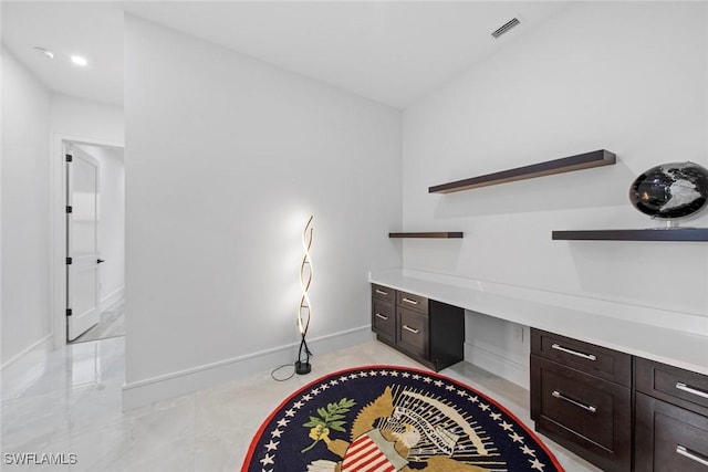 office space featuring marble finish floor, baseboards, visible vents, and built in desk