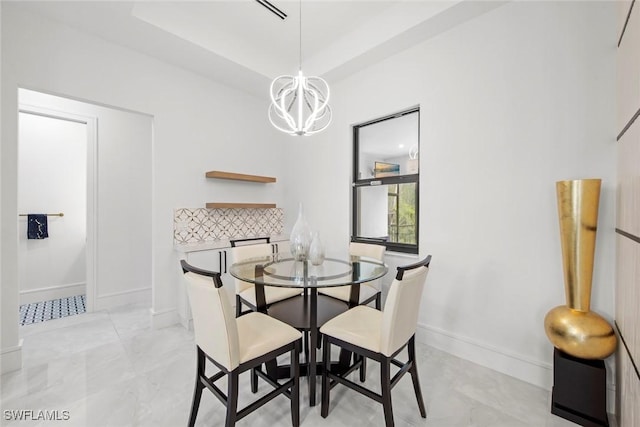 dining room with an inviting chandelier, baseboards, and a raised ceiling