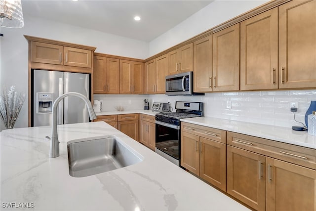 kitchen featuring stainless steel appliances, brown cabinetry, a sink, and decorative backsplash