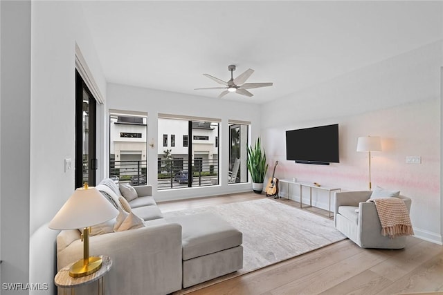 living area featuring wood finished floors, a ceiling fan, and baseboards