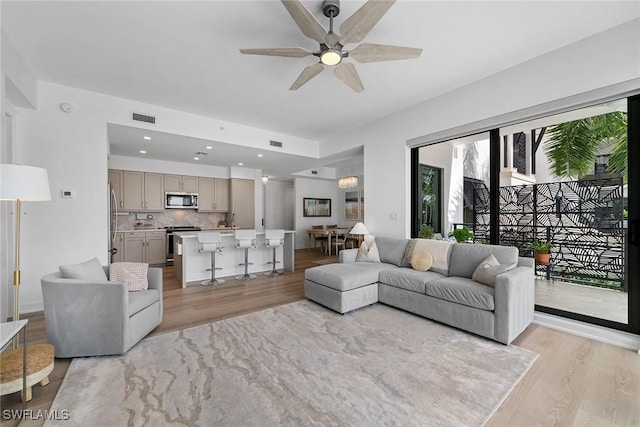 living area featuring a ceiling fan, recessed lighting, visible vents, and light wood finished floors