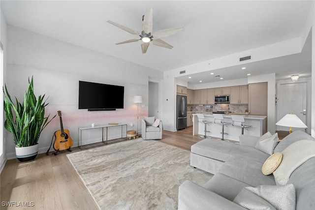 living area with light wood finished floors, visible vents, a ceiling fan, and recessed lighting