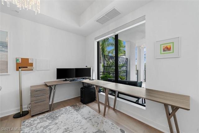 office area with a chandelier, visible vents, baseboards, and wood finished floors