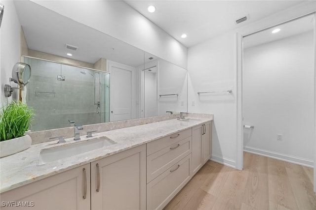 bathroom with wood finished floors, a stall shower, a sink, and visible vents