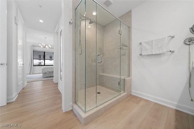 ensuite bathroom with a stall shower, ensuite bath, baseboards, and wood finished floors