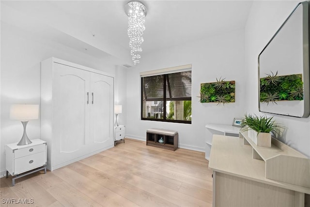 interior space with a chandelier, baseboards, and light wood finished floors