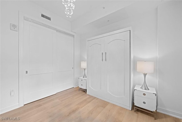 unfurnished bedroom with baseboards, a closet, visible vents, and wood finished floors