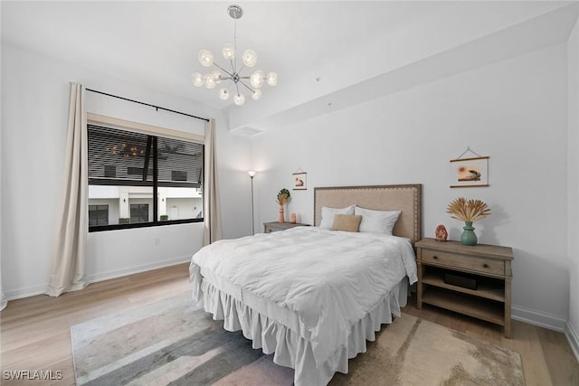 bedroom featuring a chandelier, baseboards, and wood finished floors