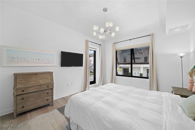 bedroom with access to exterior, a notable chandelier, baseboards, and wood finished floors