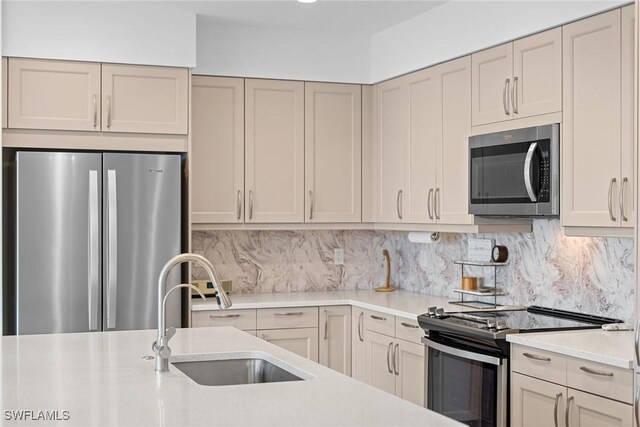 kitchen with backsplash, stainless steel appliances, a sink, and light countertops