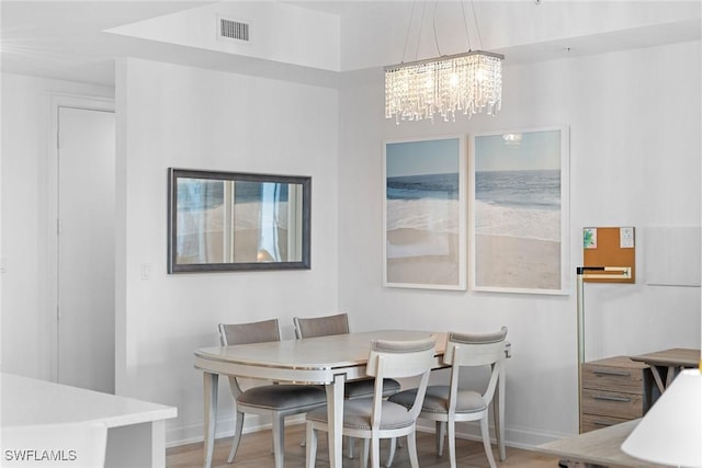 dining area featuring baseboards, wood finished floors, visible vents, and an inviting chandelier