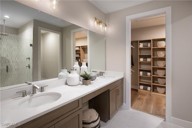 bathroom with a shower stall, a spacious closet, double vanity, and a sink