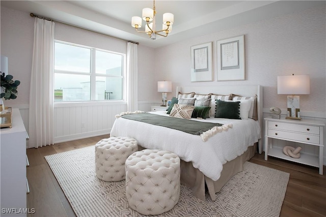 bedroom featuring an inviting chandelier, wood finished floors, and wainscoting