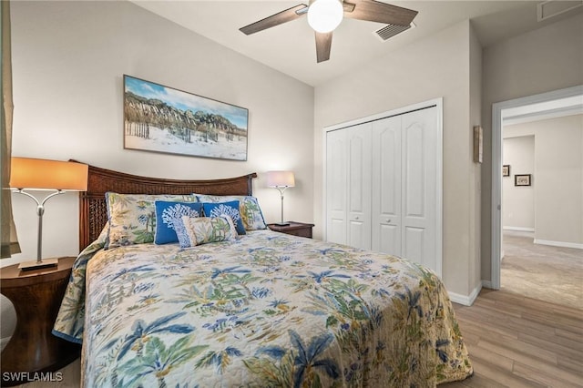 bedroom with a closet, visible vents, a ceiling fan, wood finished floors, and baseboards