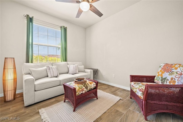 living room with ceiling fan, baseboards, and wood finished floors