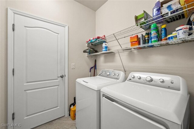 clothes washing area featuring laundry area, light tile patterned flooring, and washing machine and clothes dryer