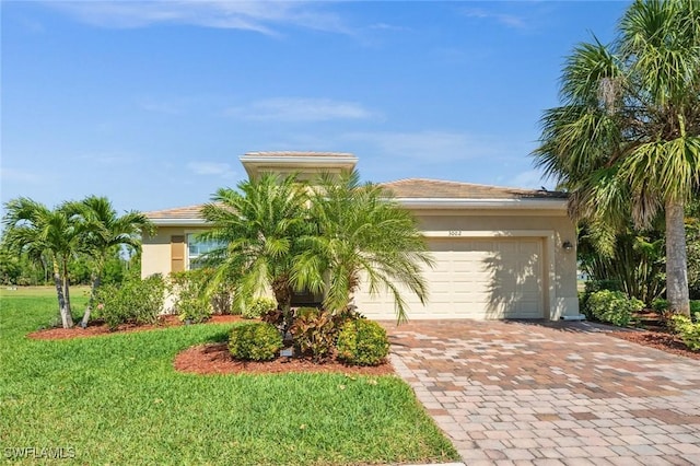 view of front of property featuring a garage, decorative driveway, a front lawn, and stucco siding