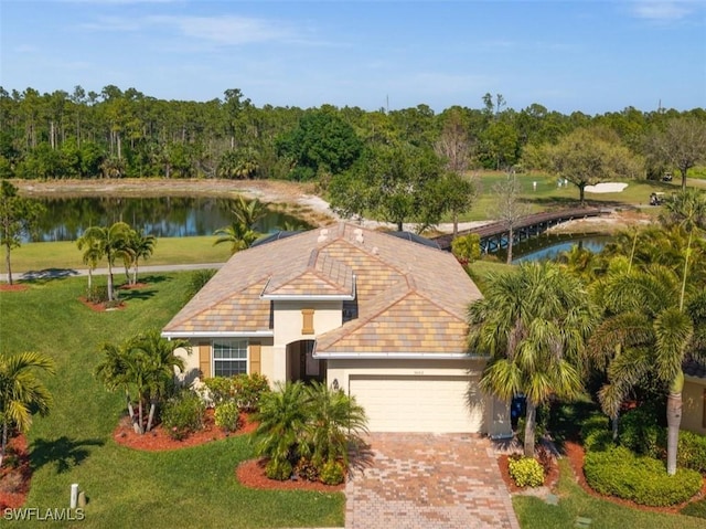 view of front of home with a water view, an attached garage, decorative driveway, a front lawn, and stucco siding