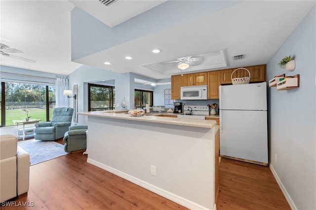 kitchen featuring visible vents, white appliances, a raised ceiling, and a ceiling fan