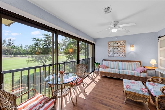 sunroom featuring a barn door, visible vents, and ceiling fan